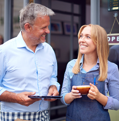man and woman smiling in cafe discussing ideas while holding a tablet and a coffee cup 6 ways to engage customers